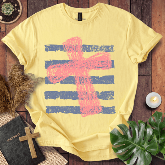 Distressed pink cross over blue horizontal stripes on a t-shirt, styled with a Bible and wooden cross.