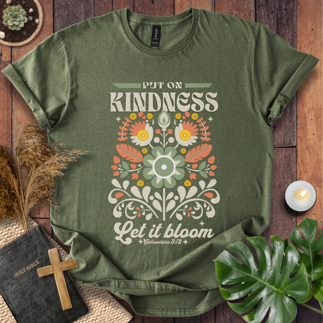 “Put On Kindness — Let It Bloom” Colossians 3:12 retro floral Christian t-shirt in folk-art style.