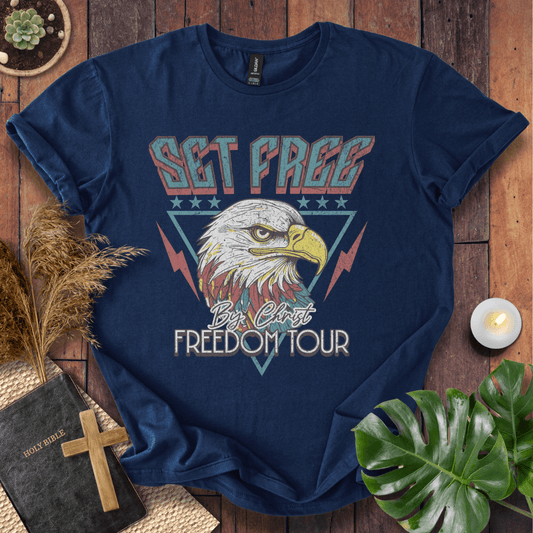 “Christian t-shirt with vintage eagle and ‘Set Free by Christ Freedom Tour’ design, styled as a flat lay with Bible and rustic Western elements.”
