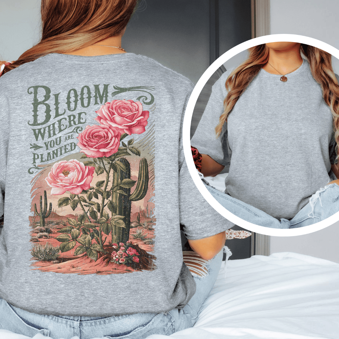Back of a t-shirt featuring pink roses, green saguaro cacti, and text reading Bloom Where You Are Planted.