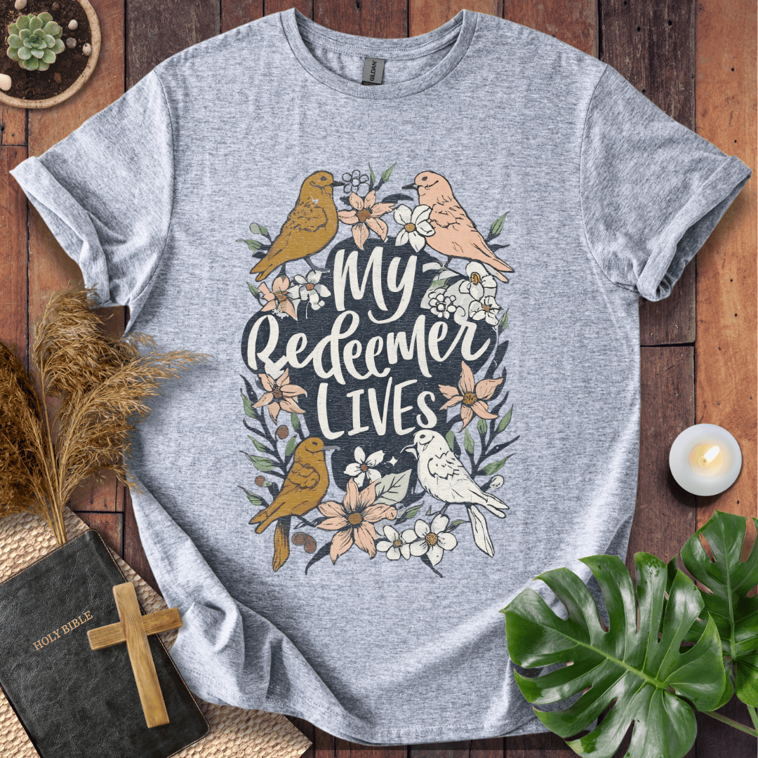 Christian Easter t-shirt with My Redeemer Lives text and birds on a wooden table next to a Holy Bible and a wooden cross.