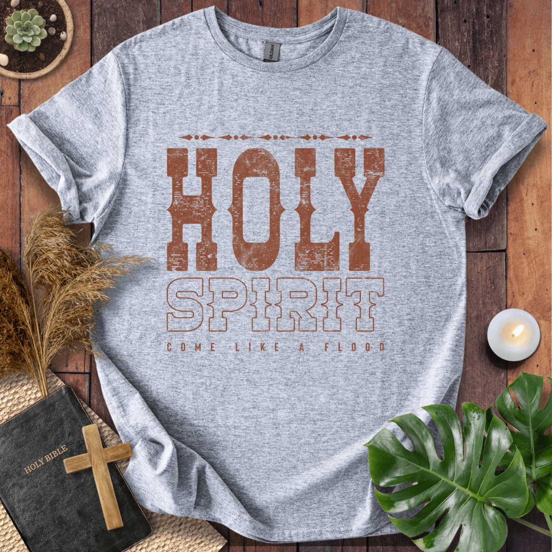 Christian t-shirt with "Holy Spirit Come Like A Flood" in distressed brown western font on a rustic wood background.