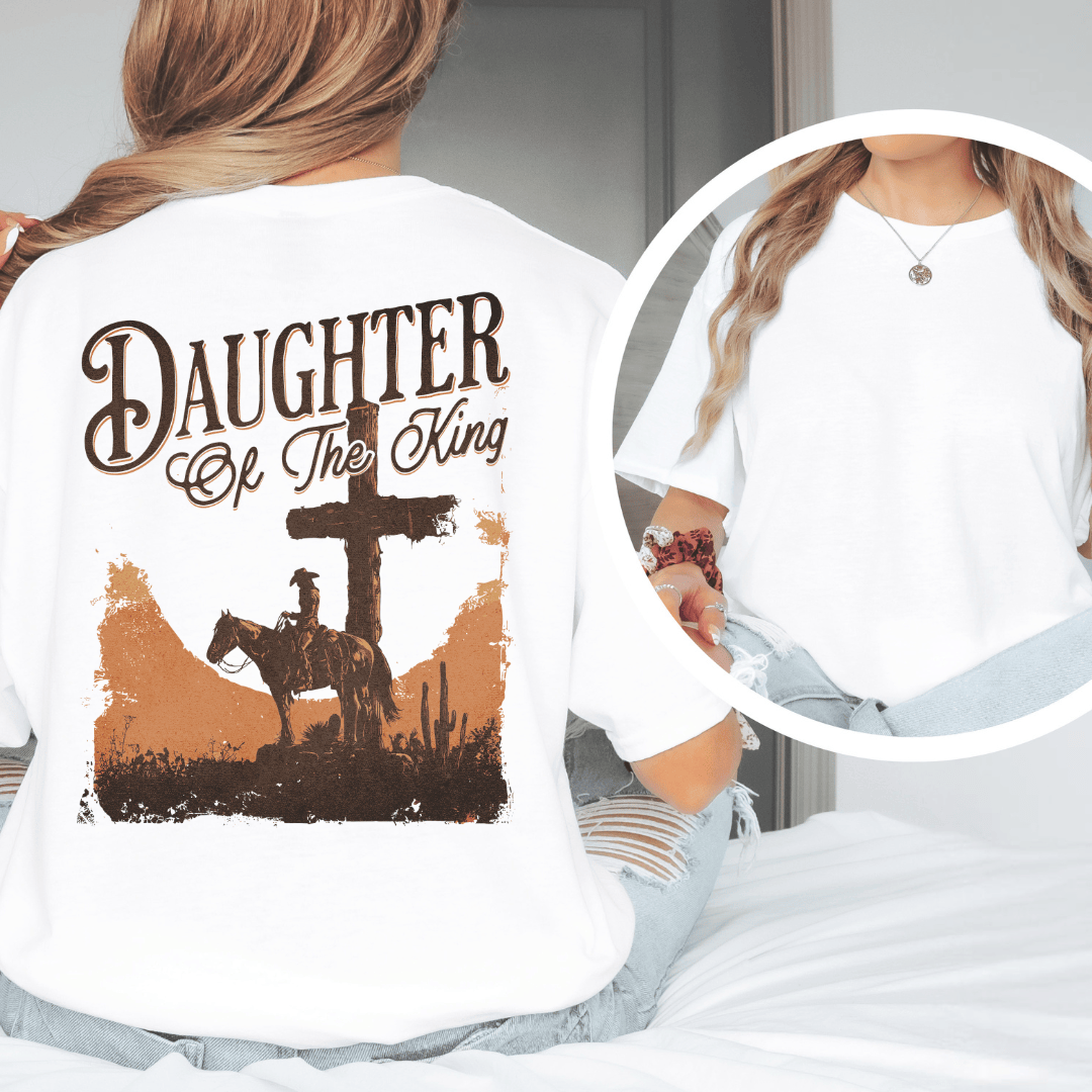 A woman wearing a graphic t-shirt with a western desert cross, cowboy on a horse, and Daughter of the King text.