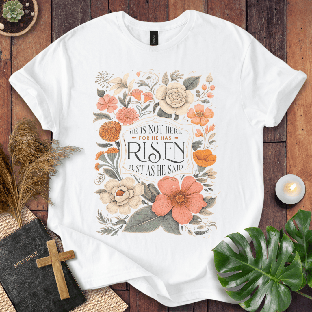 Christian Easter t-shirt with vintage flowers and He Is Risen Matthew 28:6 text on a rustic wood background.