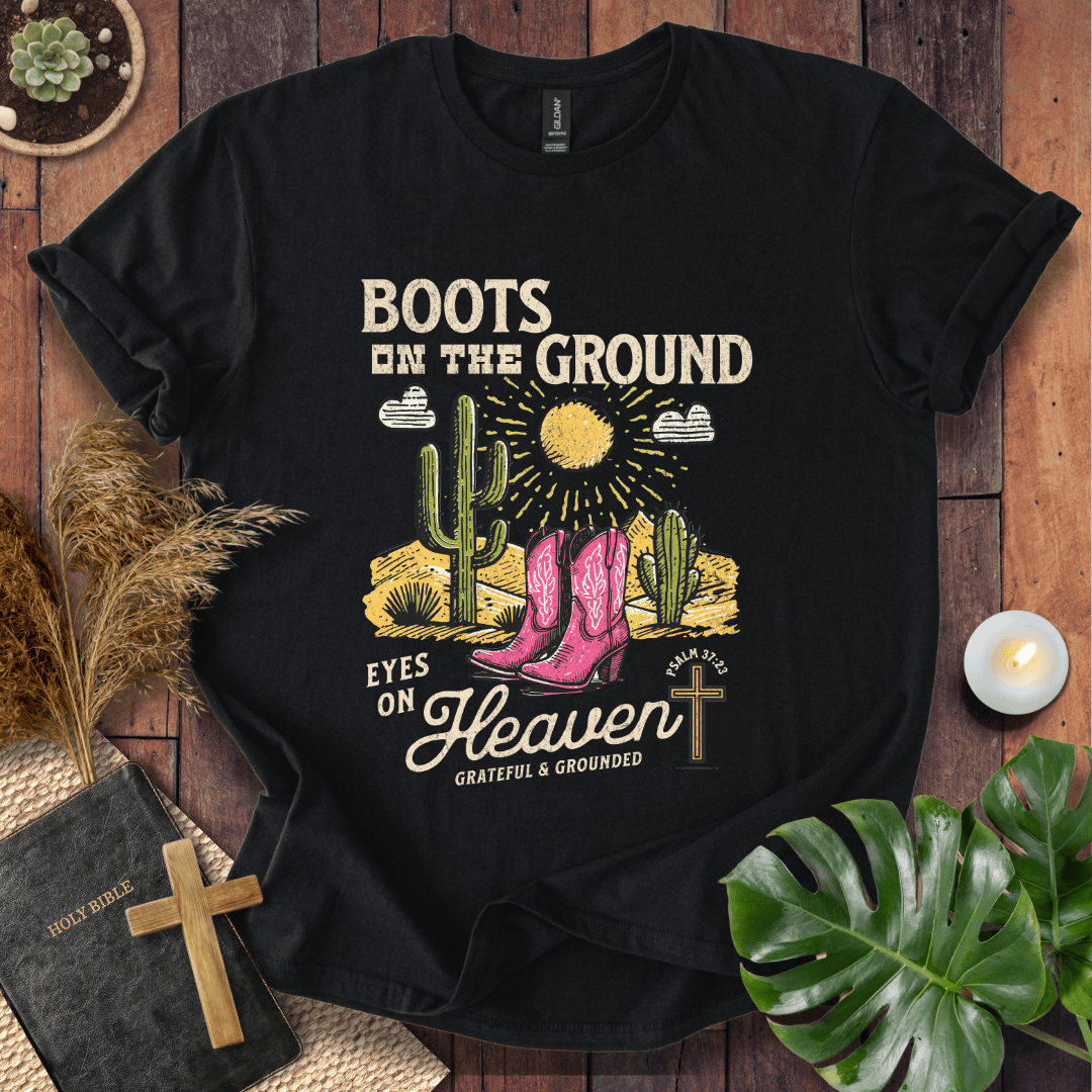 Christian t-shirt with pink cowboy boots, cacti, and "Boots on the Ground Eyes on Heaven" text for women's faith fashion.