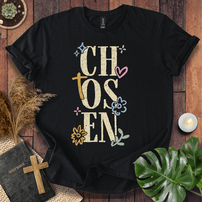 Distressed "CHOSEN" graphic on a t-shirt with a rustic gold cross and colorful boho wildflowers.