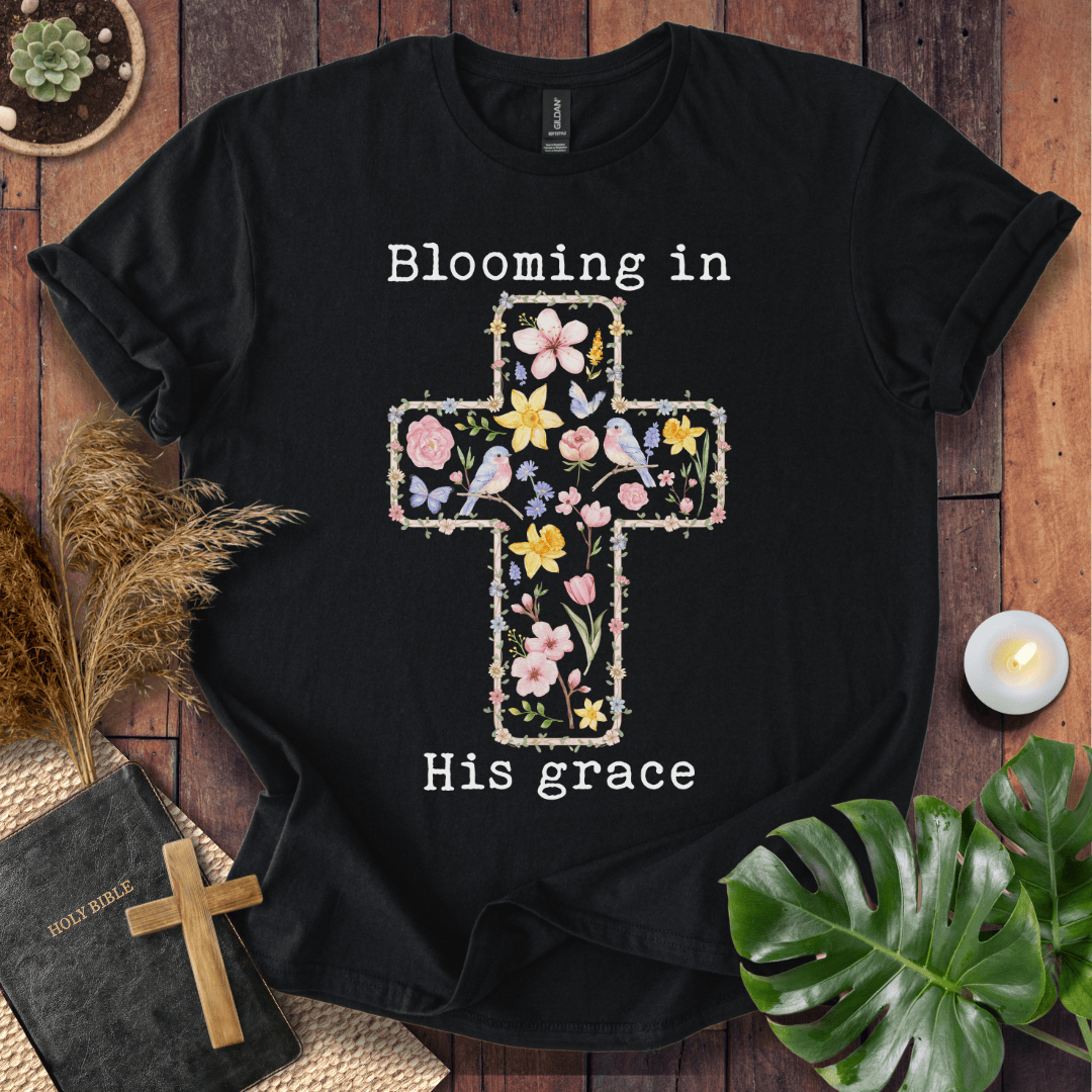 t-shirt featuring a cross filled with colorful wildflowers and birds, with the text "Blooming in His grace".