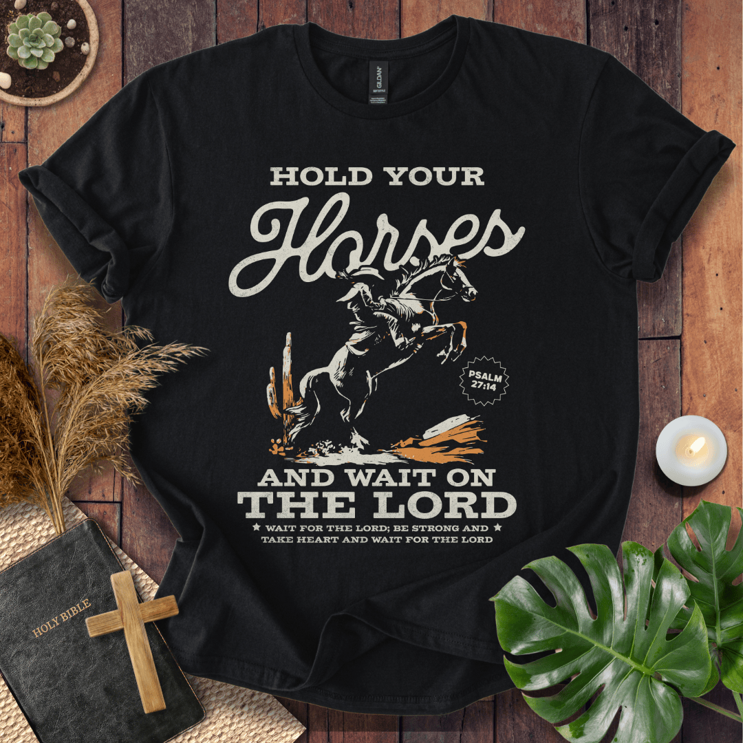 Black western t-shirt featuring a cowboy on a rearing horse with the text Hold Your Horses and Psalm 27:14 bible verse.