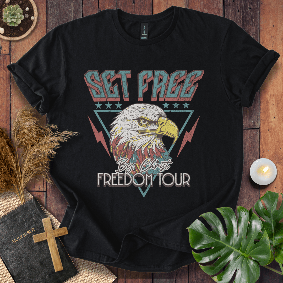 “Christian t-shirt with vintage eagle and ‘Set Free by Christ Freedom Tour’ design, styled as a flat lay with Bible and rustic Western elements.”