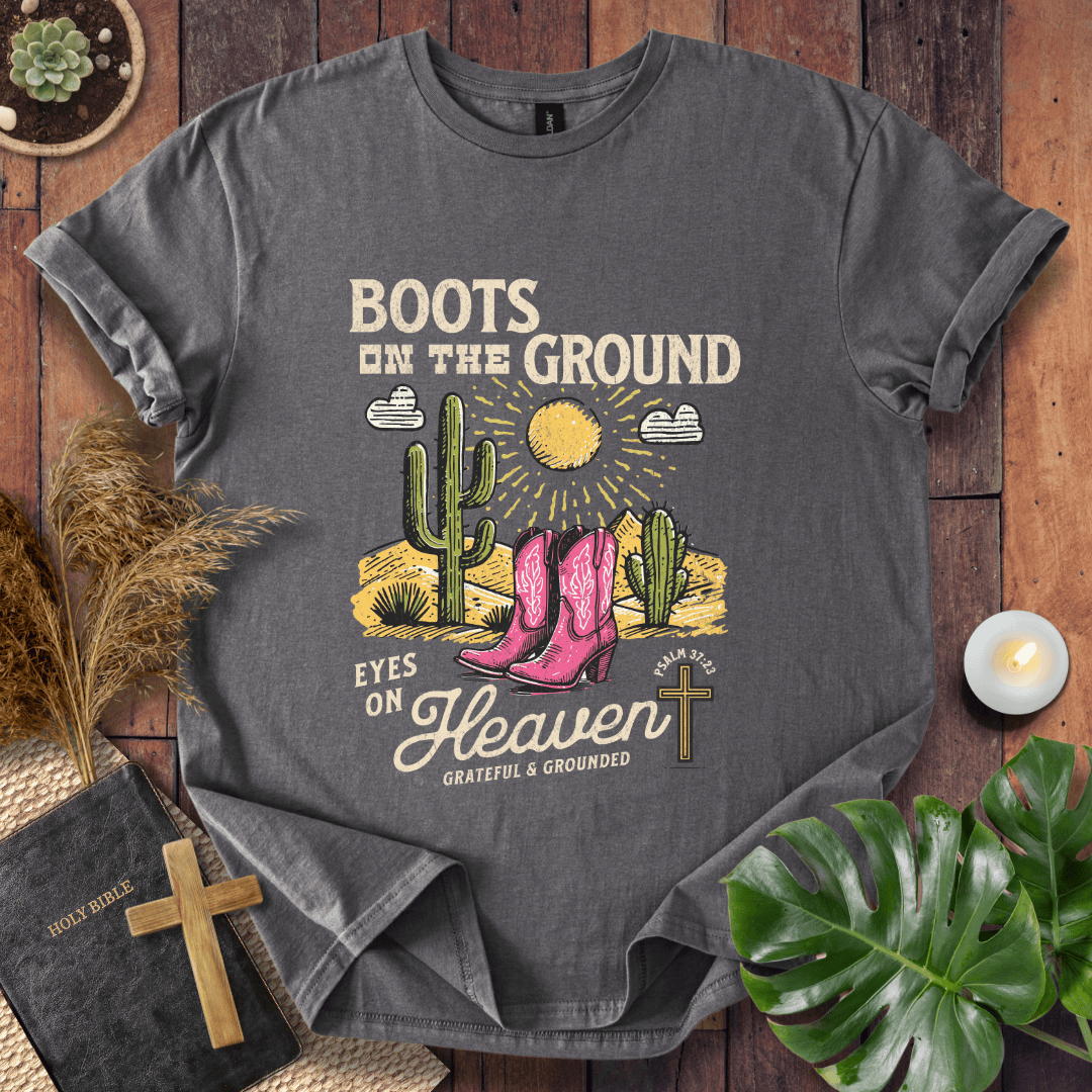 Christian t-shirt with pink cowboy boots, cacti, and "Boots on the Ground Eyes on Heaven" text for women's faith fashion.