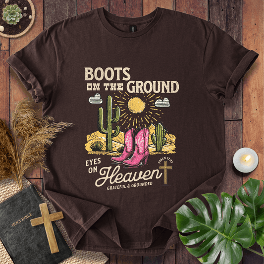 Christian t-shirt with pink cowboy boots, cacti, and "Boots on the Ground Eyes on Heaven" text for women's faith fashion.