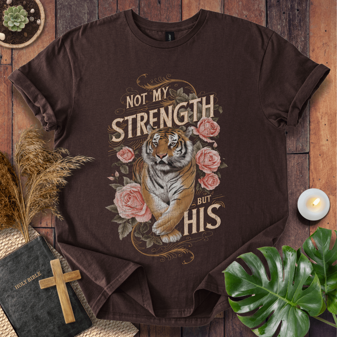 Not My Strength But His Christian t-shirt in black—tiger with roses and vintage script faith design.