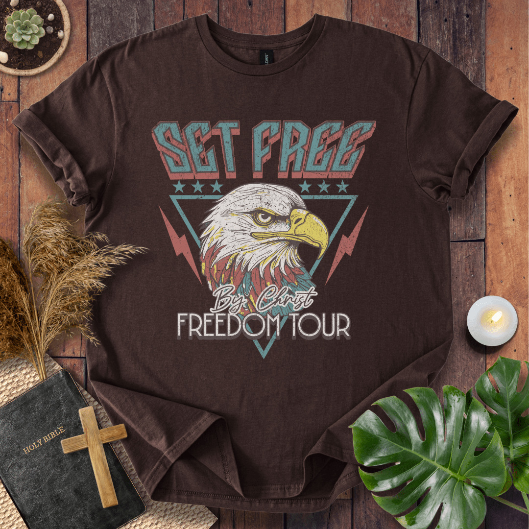 “Christian t-shirt with vintage eagle and ‘Set Free by Christ Freedom Tour’ design, styled as a flat lay with Bible and rustic Western elements.”