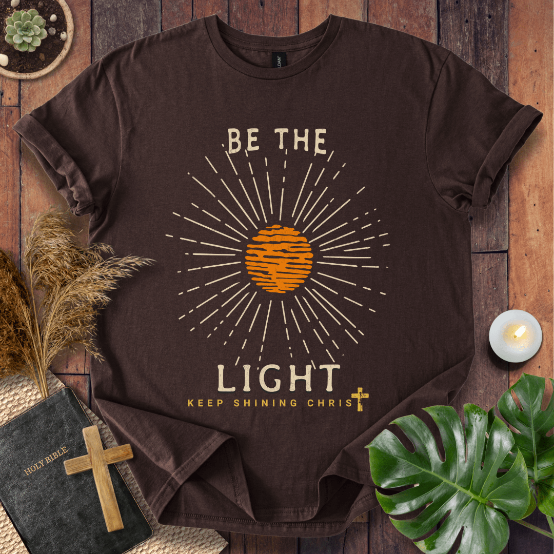 Be the Light Christian t-shirt—radiant sunburst with “Keep Shining Christ,” inspired by Matthew 5:14–16.