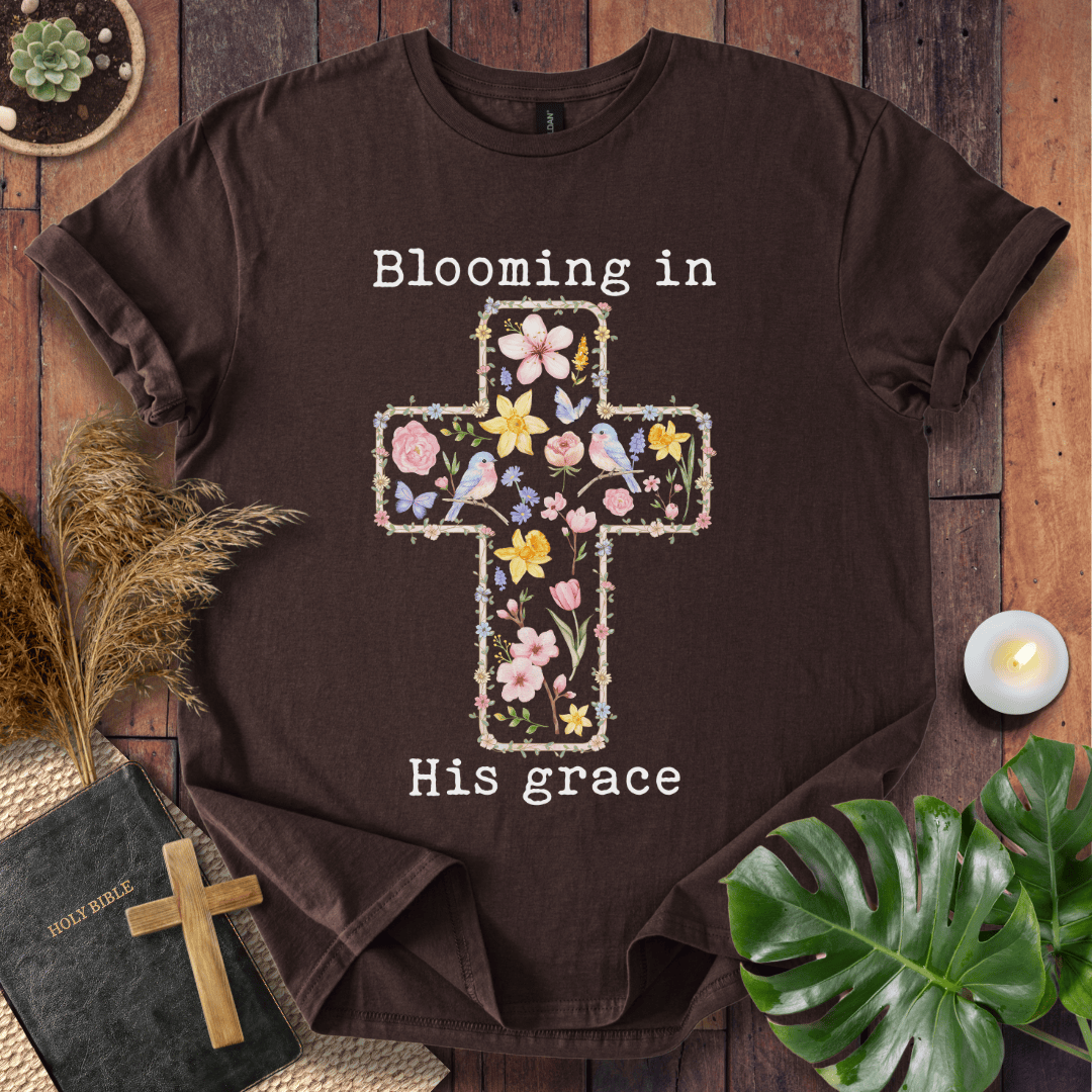 t-shirt featuring a cross filled with colorful wildflowers and birds, with the text "Blooming in His grace".