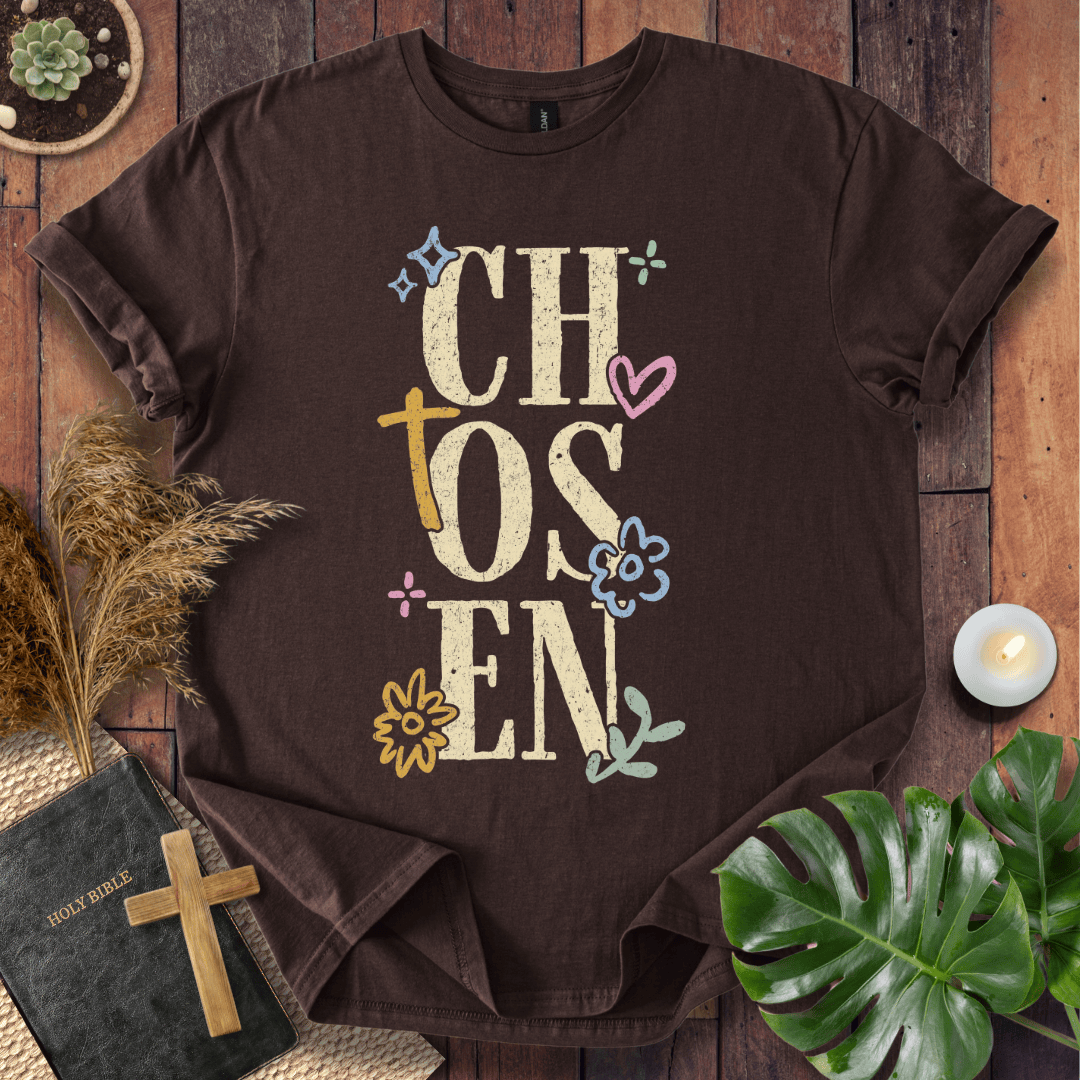 Distressed "CHOSEN" graphic on a t-shirt with a rustic gold cross and colorful boho wildflowers.