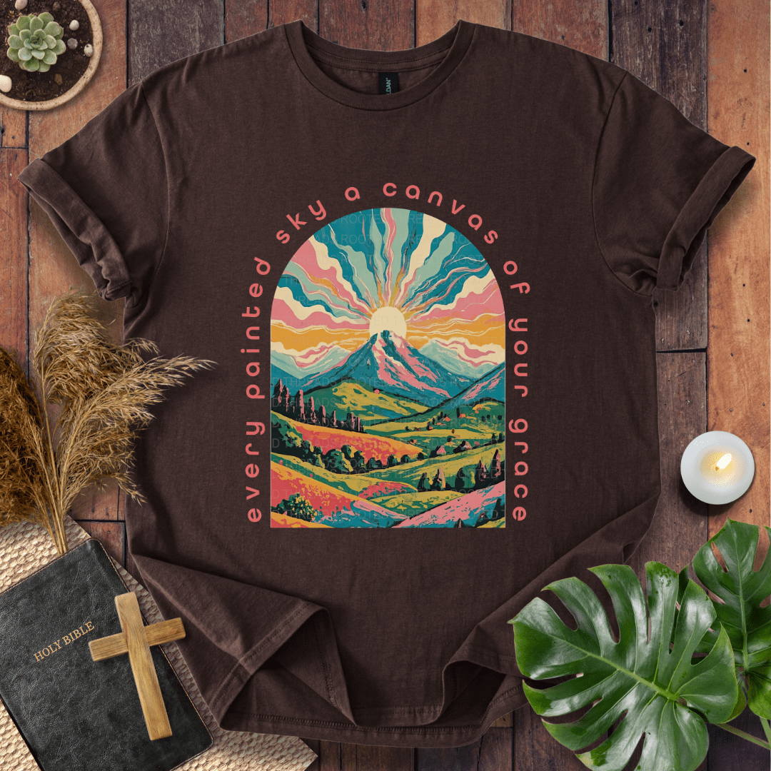 “Every painted sky a canvas of Your grace” Christian t-shirt—arched mountain sunrise with rays, rolling hills, floral accents.