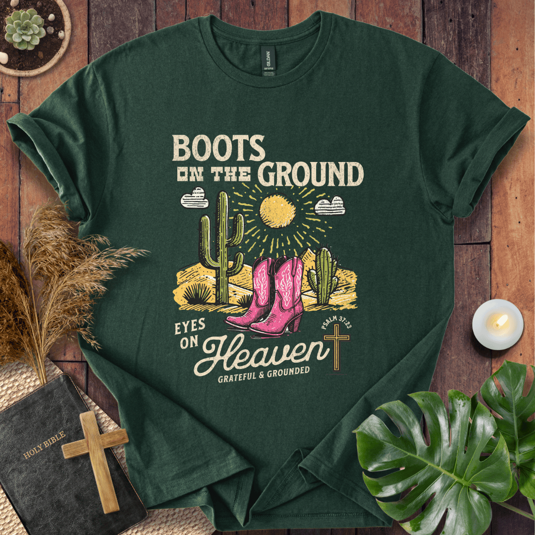 Christian t-shirt with pink cowboy boots, cacti, and "Boots on the Ground Eyes on Heaven" text for women's faith fashion.