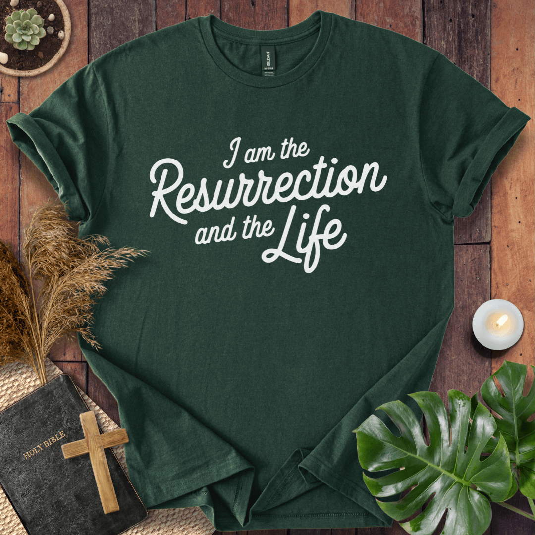 Christian t shirt for women featuring white script 'I am the Resurrection and the Life' on a rustic wood table.