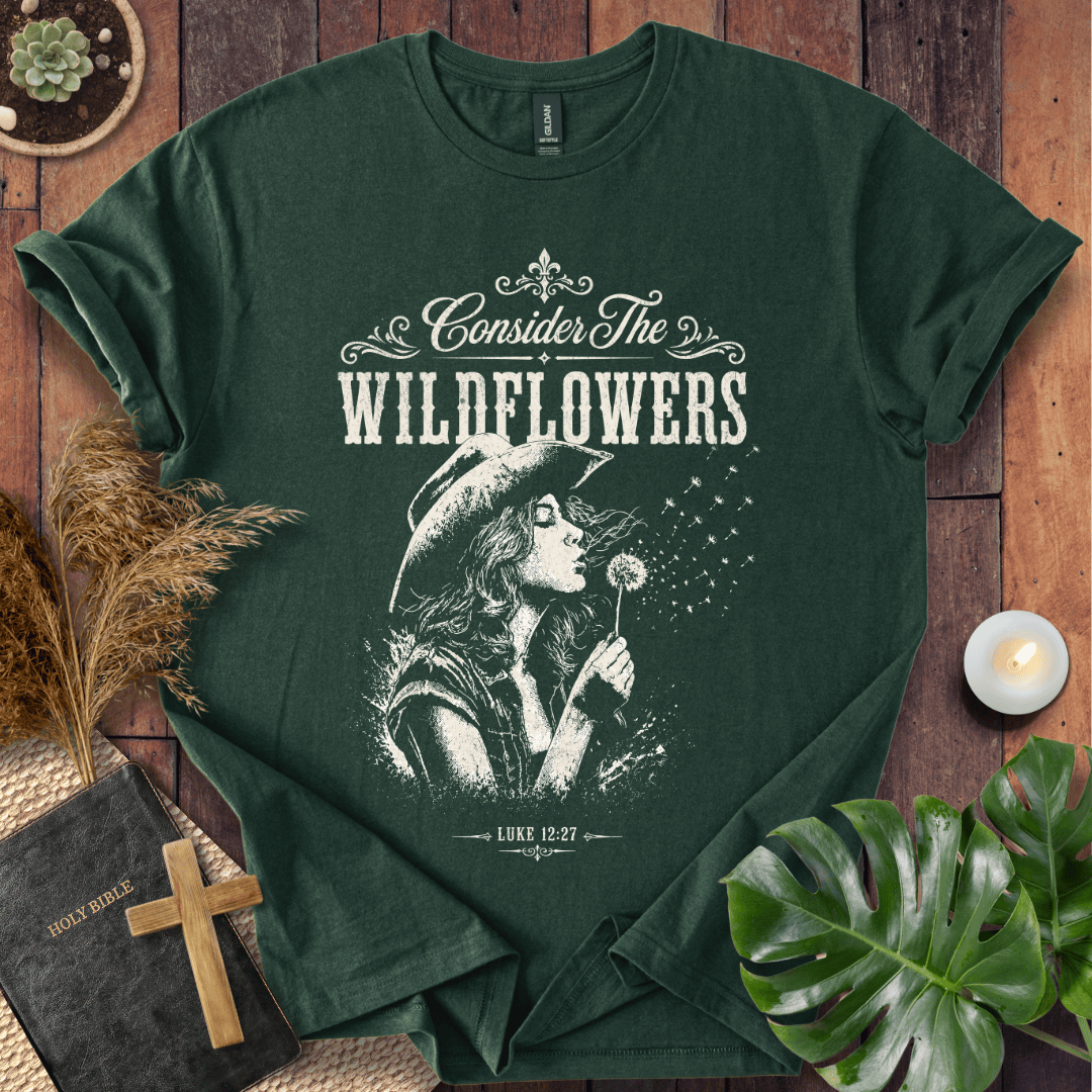 graphic tee reading Consider the Wildflowers Luke 12:27, featuring a woman in a cowboy hat blowing a dandelion.