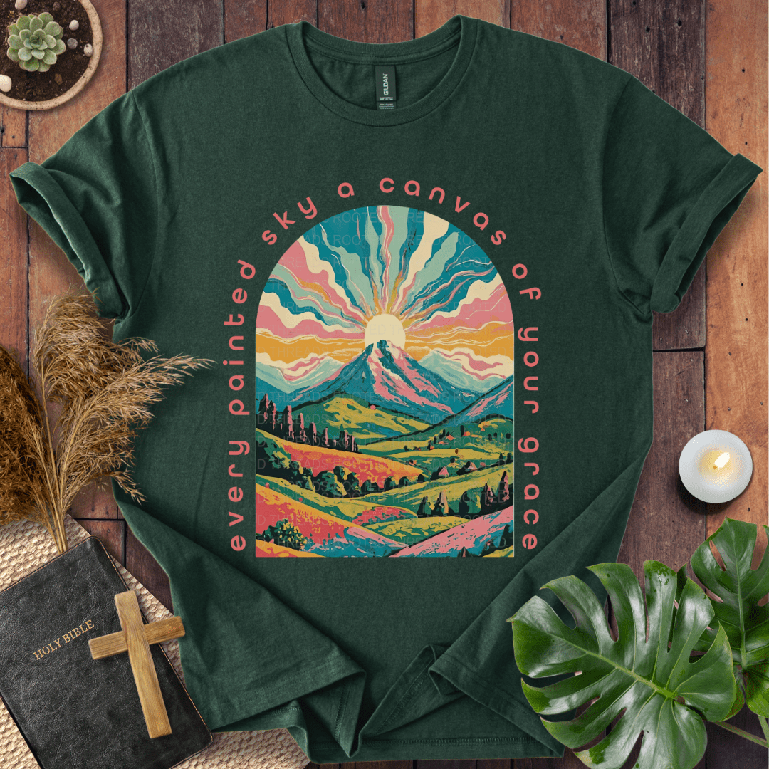 “Every painted sky a canvas of Your grace” Christian t-shirt—arched mountain sunrise with rays, rolling hills, floral accents.