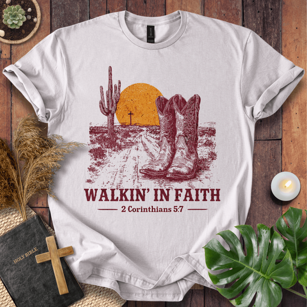 White t-shirt with desert graphic and 'Walkin' in Faith' text on a wooden surface.