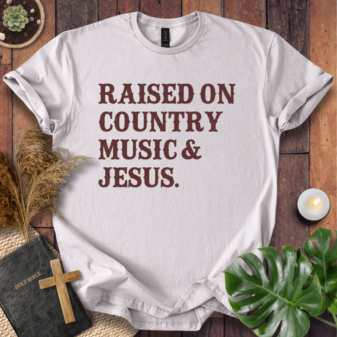 Christian t shirts for women with "Raised on Country Music & Jesus" in brown text on a rustic wood background.