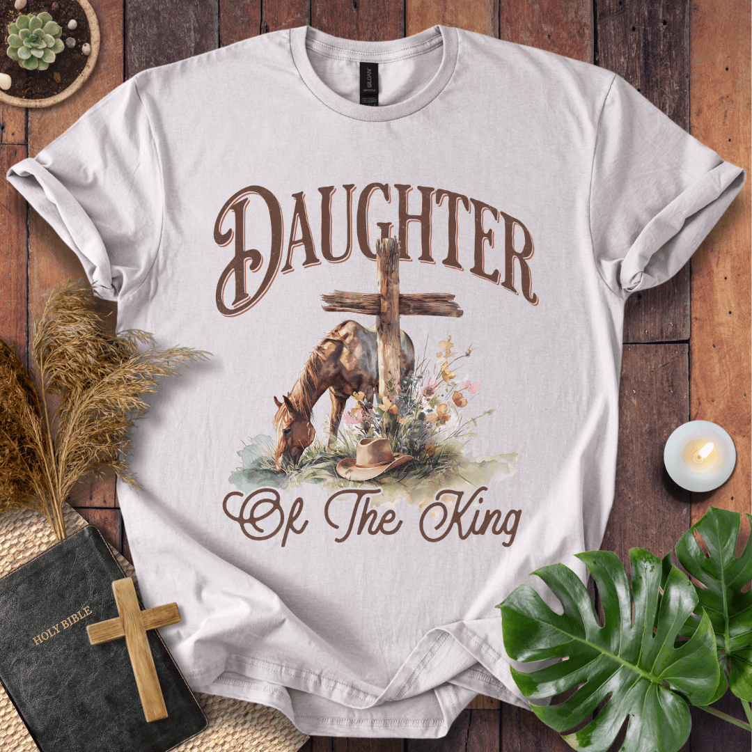 t-shirt with "Daughter of the King" text, a grazing horse, wooden cross, cowboy hat, and wildflowers.