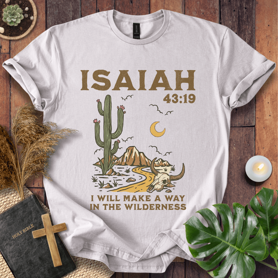 White t-shirt with cactus and mountain design and 'Isaiah 43:19' text on a wooden surface.