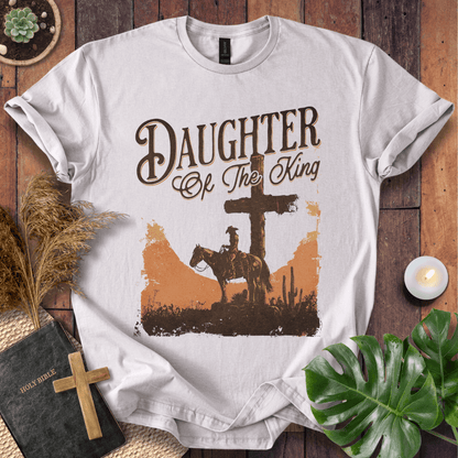Western Christian t shirt for women featuring a rider on a horse by a cross in a desert sunset.