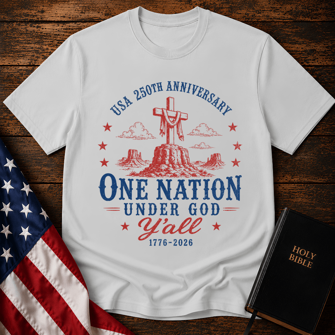 Patriotic western graphic tee featuring a wooden cross on a desert mesa with text One Nation Under God Y'all 1776-2026.
