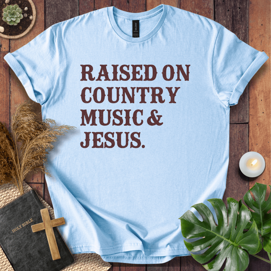 Christian t shirts for women with "Raised on Country Music & Jesus" in brown text on a rustic wood background.