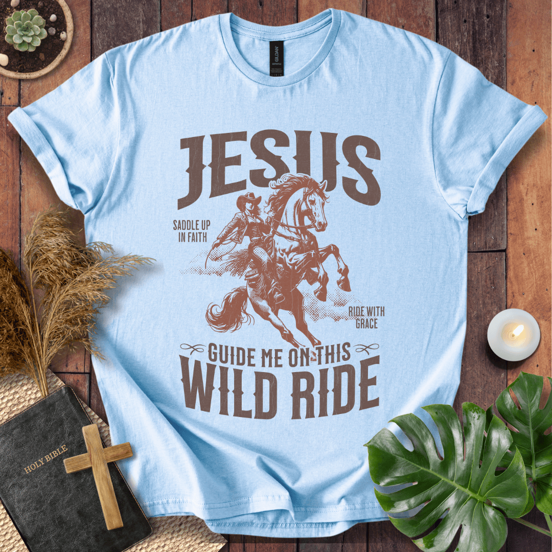 Light blue t-shirt with a graphic of a horse and text on a wooden surface with decor items.