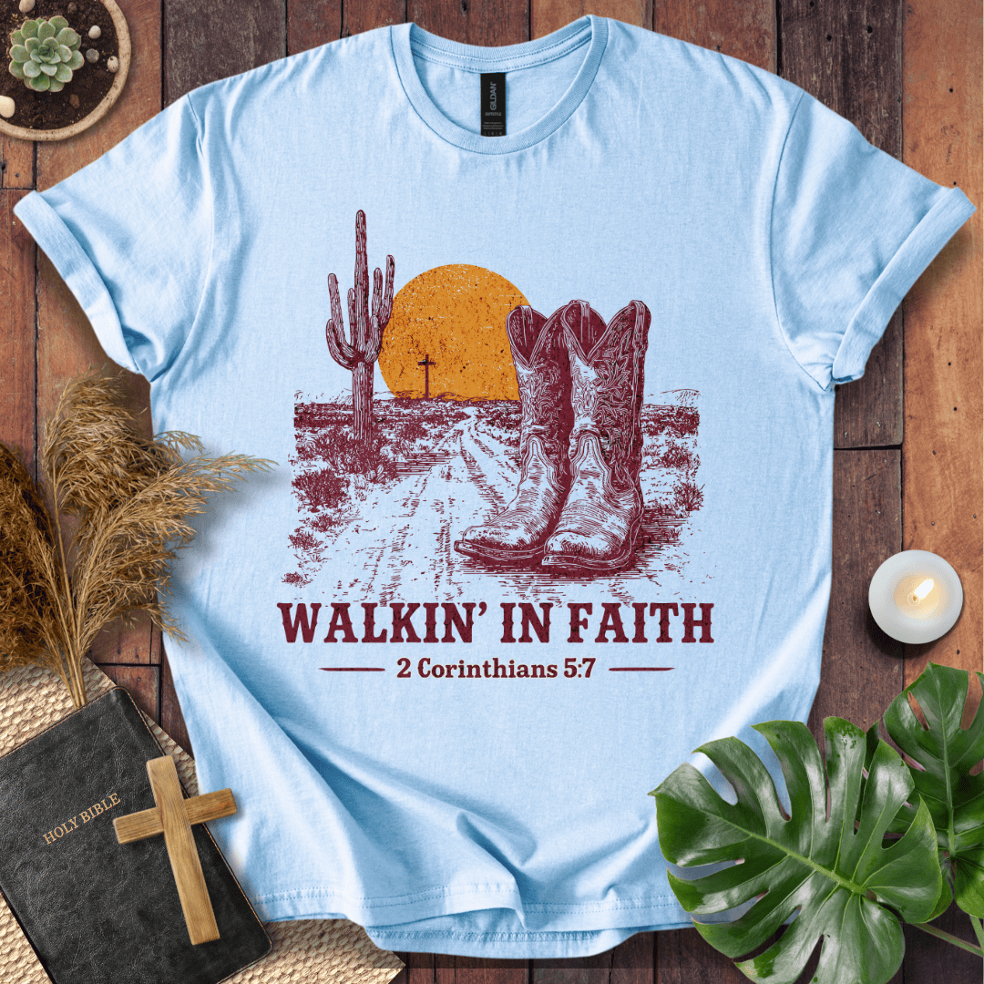 Light blue t-shirt with cowboy boots and desert design, featuring 'Walkin' in Faith' text on a wooden surface.