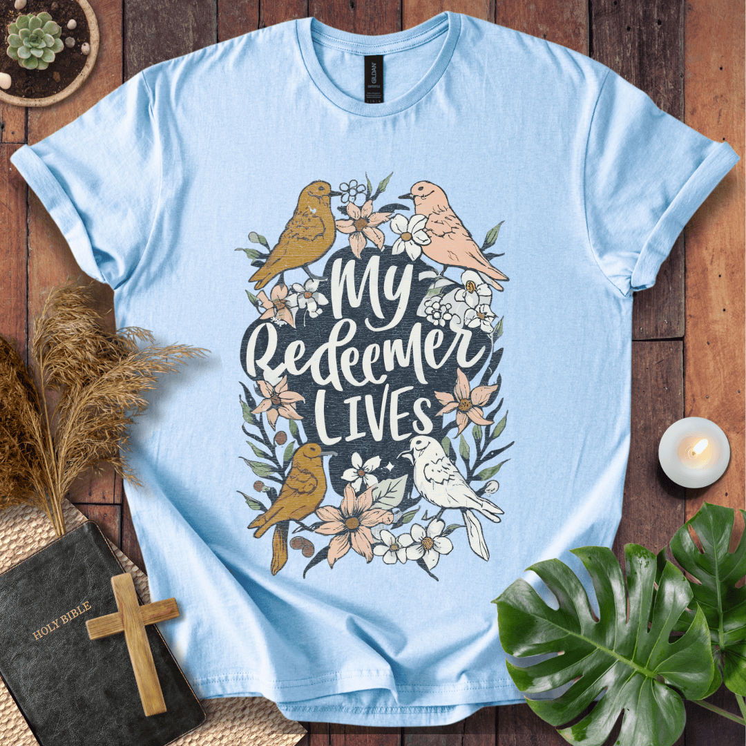 Christian Easter t-shirt with My Redeemer Lives text and birds on a wooden table next to a Holy Bible and a wooden cross.