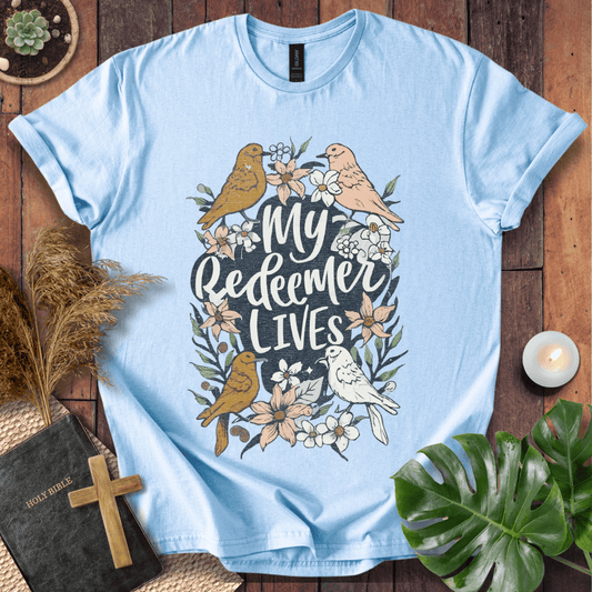 Christian Easter t-shirt with My Redeemer Lives text and birds on a wooden table next to a Holy Bible and a wooden cross.