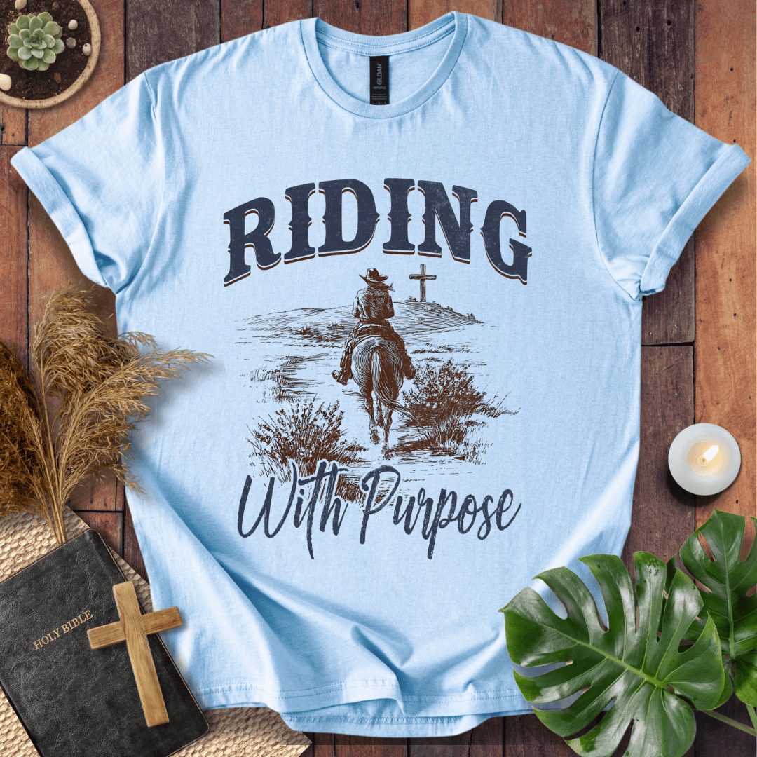 A lone rider on a horse approaching a cross on a Christian themed shirt with Riding With Purpose text.