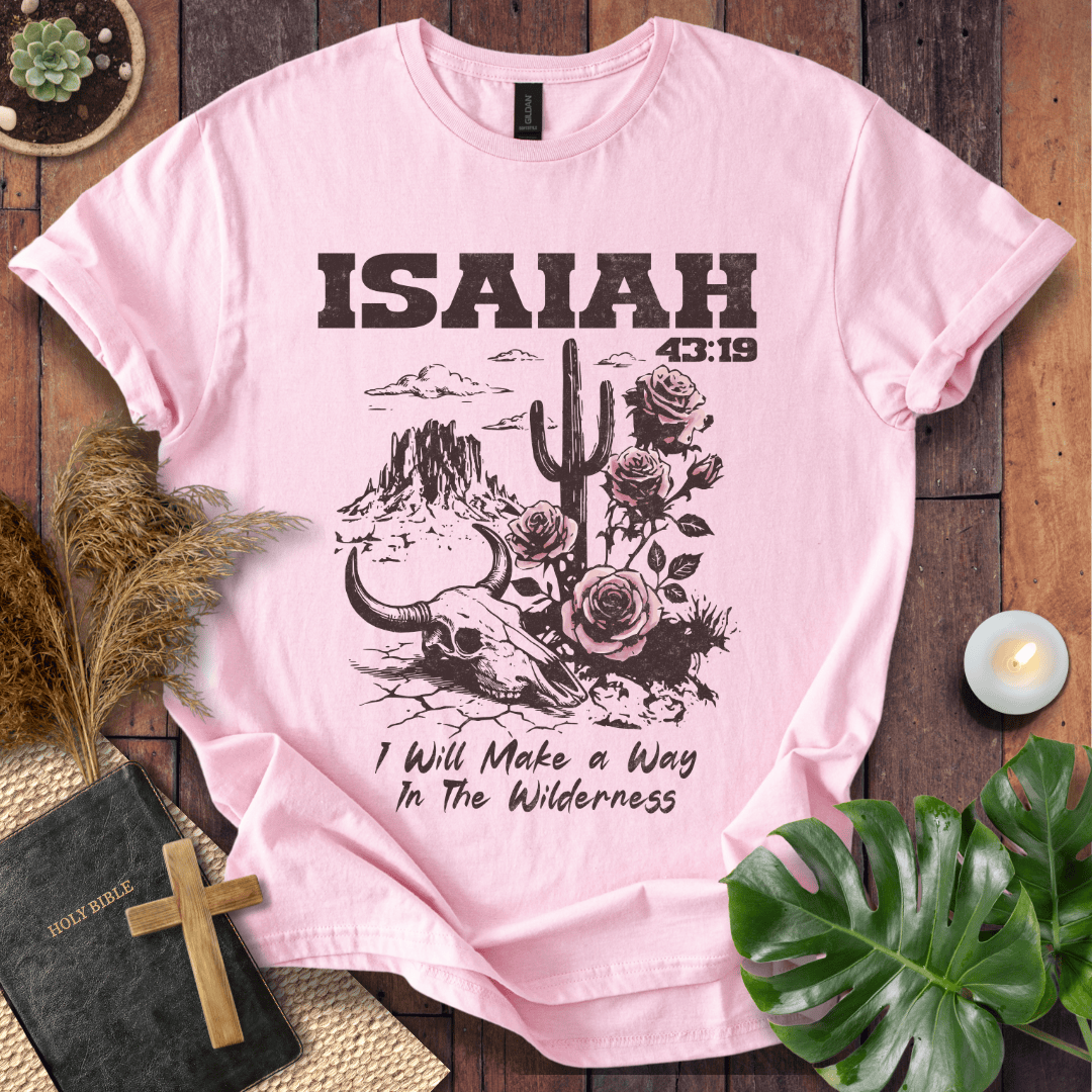 Pink t-shirt with 'ISAIAH 43:19' design on a wooden surface with plants and a Bible.