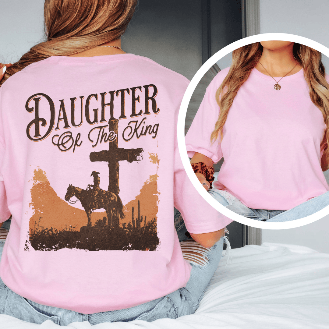 A woman wearing a graphic t-shirt with a western desert cross, cowboy on a horse, and Daughter of the King text.