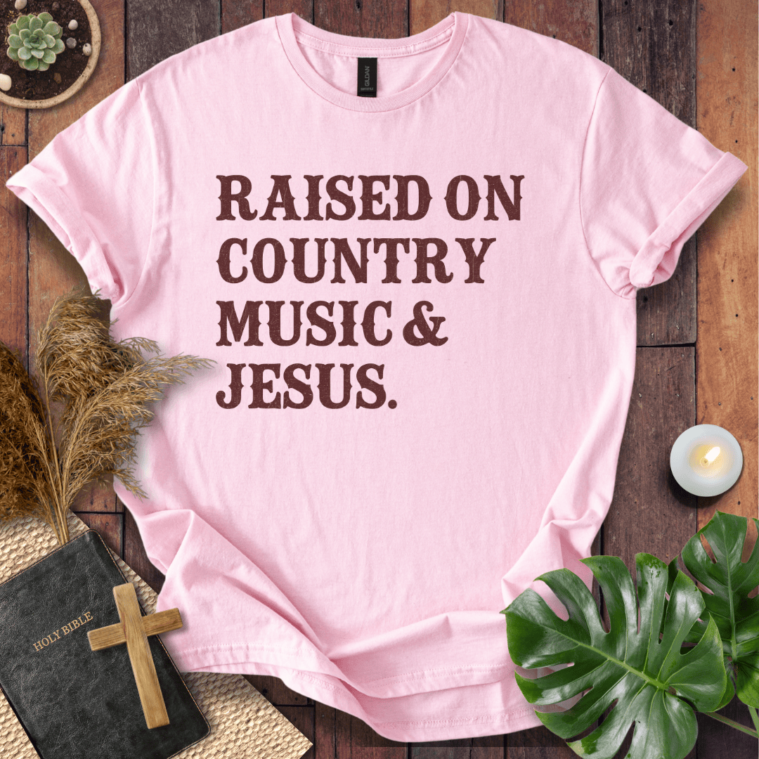 Christian t shirts for women with "Raised on Country Music & Jesus" in brown text on a rustic wood background.