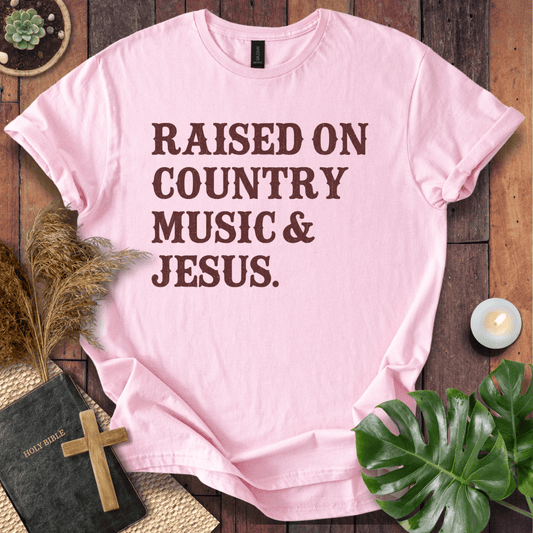 Christian t shirts for women with "Raised on Country Music & Jesus" in brown text on a rustic wood background.
