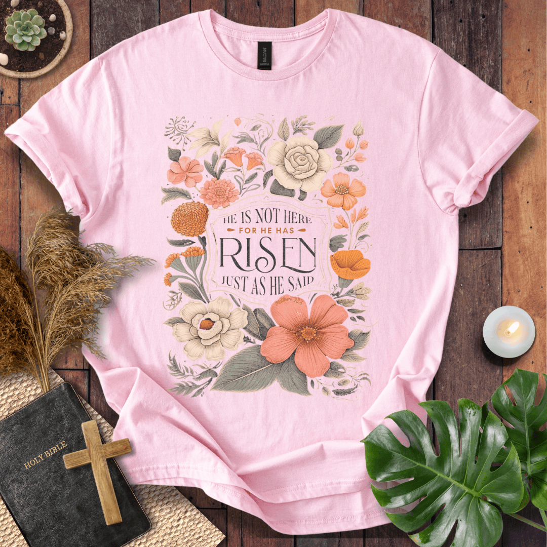 Christian Easter t-shirt with vintage flowers and He Is Risen Matthew 28:6 text on a rustic wood background.