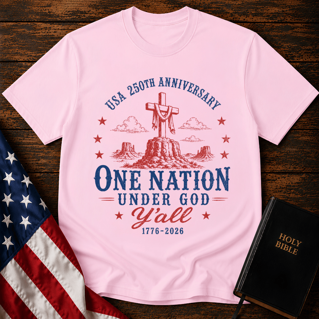 Patriotic western graphic tee featuring a wooden cross on a desert mesa with text One Nation Under God Y'all 1776-2026.