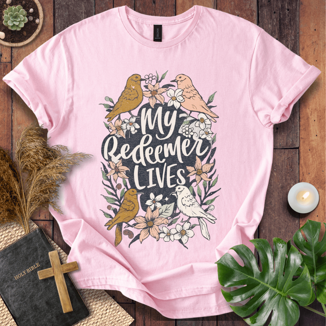 Christian Easter t-shirt with My Redeemer Lives text and birds on a wooden table next to a Holy Bible and a wooden cross.