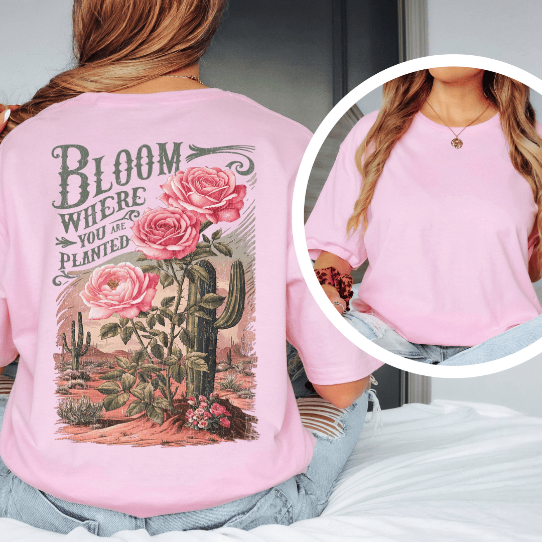 Back of a t-shirt featuring pink roses, green saguaro cacti, and text reading Bloom Where You Are Planted.