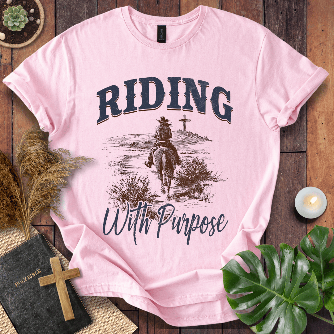 A lone rider on a horse approaching a cross on a Christian themed shirt with Riding With Purpose text.
