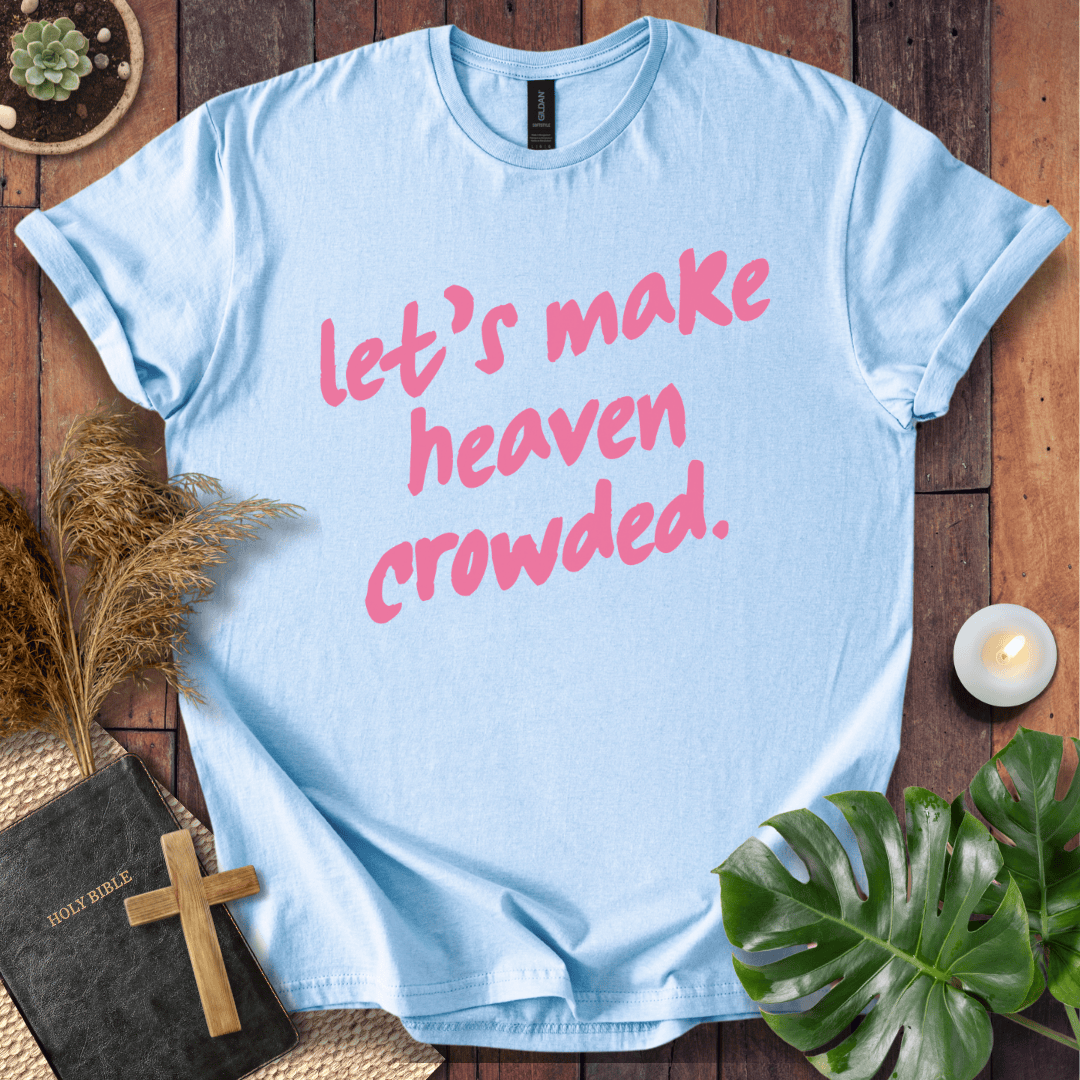 A light blue crewneck t-shirt with the phrase 'let's make heaven crowded.' printed in pink script across the front.