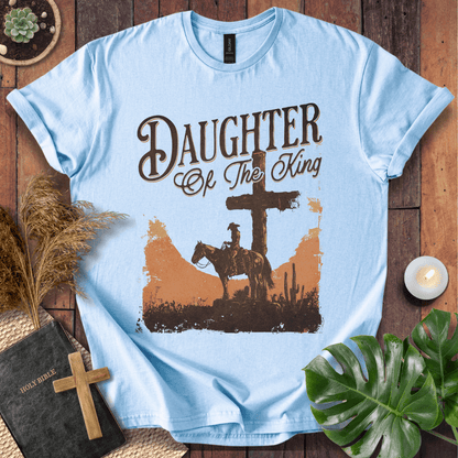 Western Christian t shirt for women featuring a rider on a horse by a cross in a desert sunset.