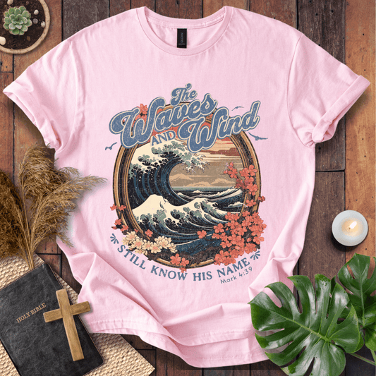 The Waves and Wind Still Know His Name Christian t-shirt in sand—vintage wave, sunset, and floral frame, Mark 4:39.