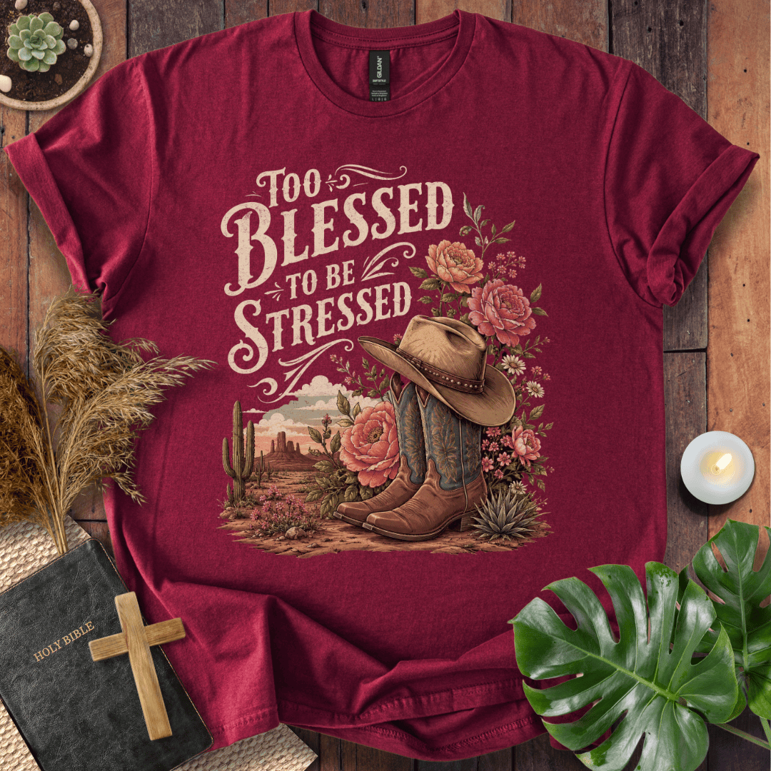 A maroon crewneck t-shirt with a western-themed graphic print reading 'Too Blessed to be Stressed'. The graphic features a cowboy hat, boots, cactus, and pink roses on a desert landscape.
